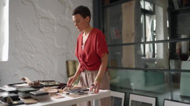 Smiling brunette woman architect puts samples on a table in the office