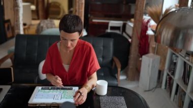 Pensive brunette woman architect with short hair working on tablet in the office