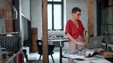 Concentrated brunette woman architect working on laptop in the office