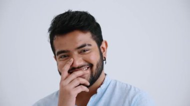 Happy Indian man with piercing wearing blue shirt looking at the camera in the grey studio