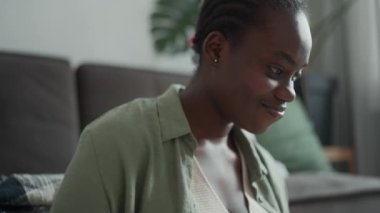 Smiling African woman with pigtails working at home