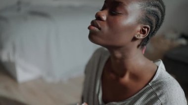 Handsome African woman with pigtails does yoga meditation at home