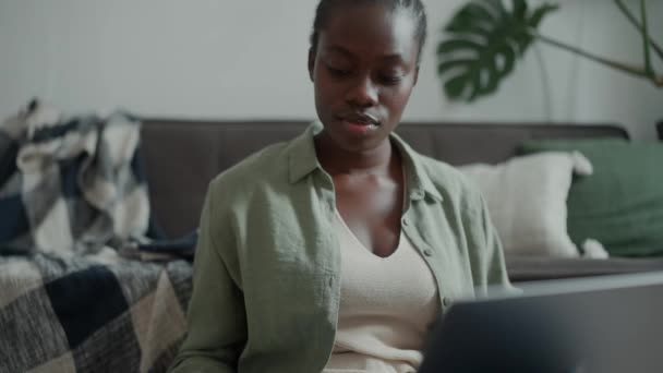 ノートパソコンで働いているピグテールと自宅でお茶を飲んでいるハンサムなアフリカの女性 — ストック動画