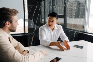 Two business people sitting by office table discussing project in modern office building