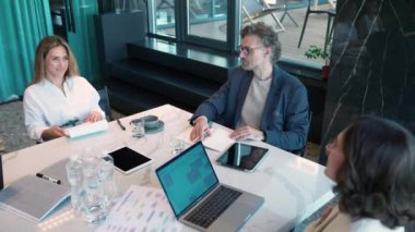 Smiling professional employees and managers discuss work at the office table