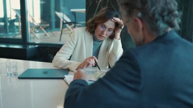 Pensive adult architectural designers talking about work while sitting in the office