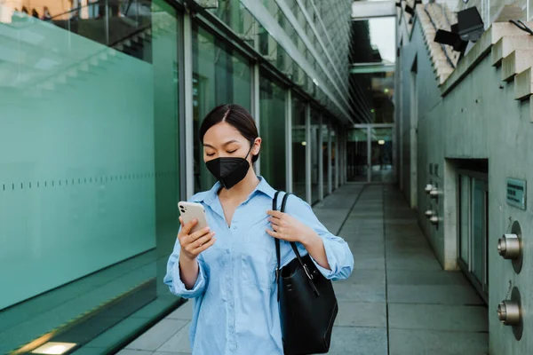 Asian Woman Face Mask Using Mobile Phone While Standing Building — Zdjęcie stockowe