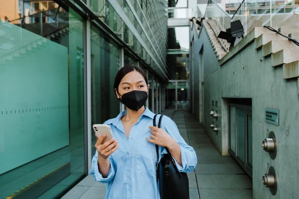 Asian Woman Face Mask Using Mobile Phone While Standing Building — Zdjęcie stockowe