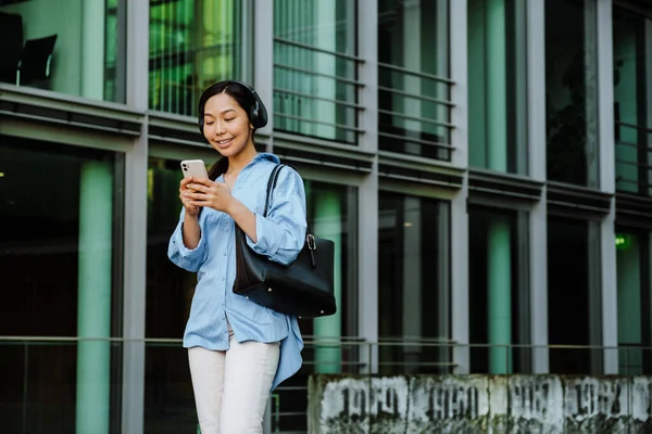Asian Brunette Woman Headphones Using Cellphone While Walking City Street — Stockfoto