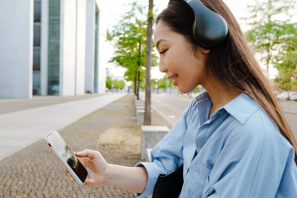 Asian Brunette Woman Headphones Using Cellphone While Sitting Bench Outdoors — Stok fotoğraf