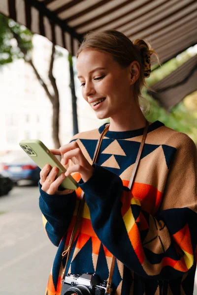 Smiling Beautiful Woman Wearing Colorful Sweater Using Smartphone While Standing —  Fotos de Stock