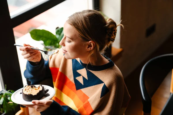 Young Blonde Woman Colorful Sweater Eating Delicious Dessert While Sitting — Fotografia de Stock