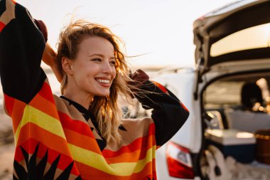 Happy young white woman smiling while walking by seashore on sunny day