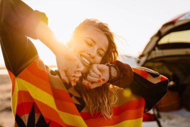 Happy young white woman smiling while walking by seashore on sunny day