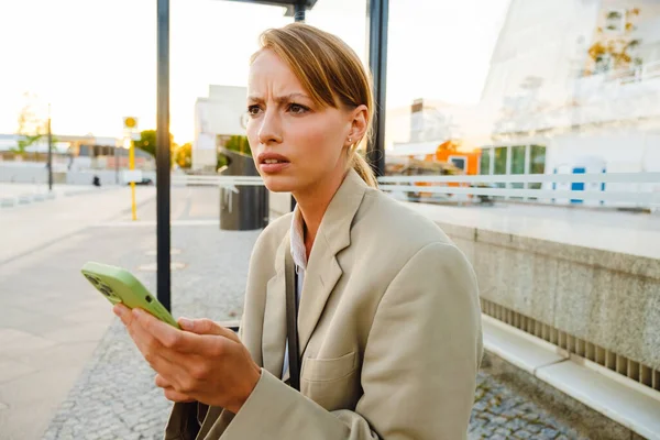 Portrait Young Beautiful Frowning Woman Holding Phone Looking Aside While — Stockfoto