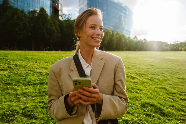 Young Beautiful Smiling Business Woman Holding Phone Looking Aside While — 图库照片