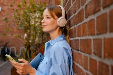 White young woman using mobile phone while resting in cafe outdoors