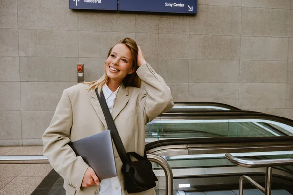 Young White Woman Smiling Holding Laptop While Standing Escalator Outdoors — Stok fotoğraf