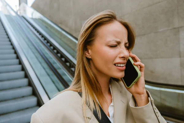 Young White Woman Frowning Talking Cellphone While Going Escalator Outdoors — Stock Photo, Image