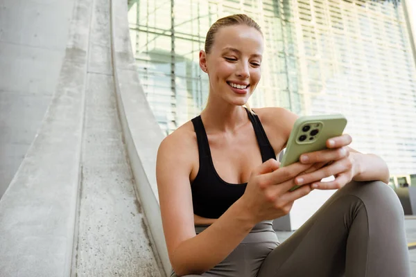 Mladá Krásná Usměvavá Šťastná Sportovní Žena Drží Používá Telefon Zatímco — Stock fotografie