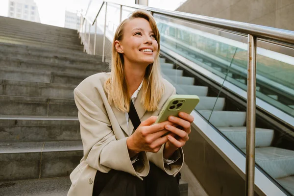 Jovem Mulher Branca Sorrindo Usando Celular Enquanto Sentado Escadas Livre — Fotografia de Stock
