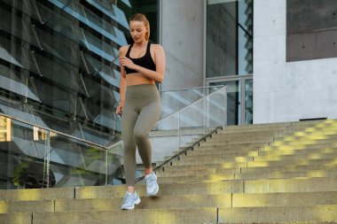 White young blond woman wearing sports bra doing workout on stairs outdoors