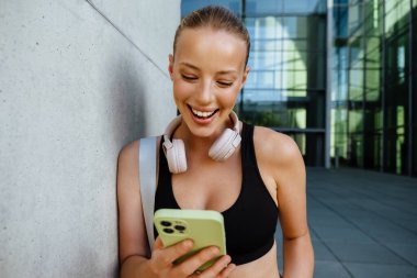 White young woman using mobile phone after yoga practice outdoors