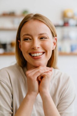 Blonde white woman smiling and looking at camera while sitting in cafe indoors