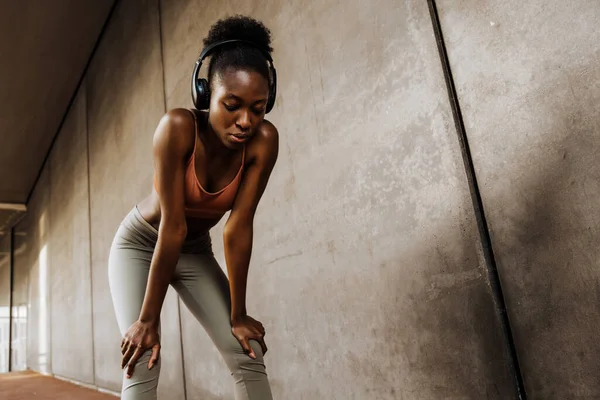 Young Sporty Calm African Woman Headphones Looking Downward While Leaning — Stok fotoğraf