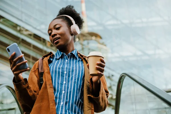 Jonge Mooie Afrikaanse Vrouw Koptelefoon Met Koffie Kijken Haar Telefoon — Stockfoto