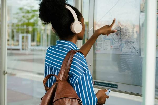 Young African Woman Headphones Backpack Standing Her Back Pointing Train — Stockfoto