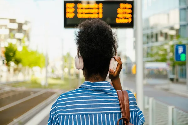 Portrait African Woman Headphones Standing Her Back Train Timetable Her — Stockfoto
