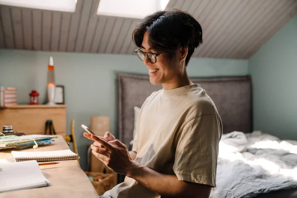 Asyalı Genç Adam Masada Otururken Evde Çalışırken Cep Telefonu Kullanıyor — Stok fotoğraf
