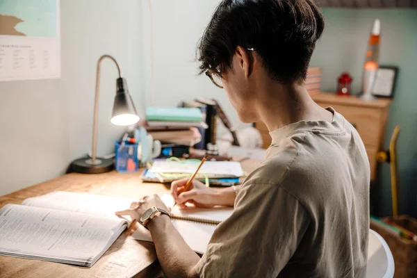 Serious Asian Teenage Guy Studying Book While Sitting Desk Home — Stok fotoğraf