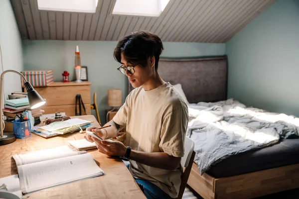 Asyalı Genç Adam Masada Otururken Evde Çalışırken Cep Telefonu Kullanıyor — Stok fotoğraf