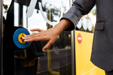 Hand pushing the blue button of the disabled people door in public transport bus outdoors