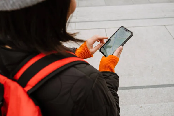 バックパック付きの若い女性の街の通りで階段に立ちながらスマートフォンを使用してのバックパックのビュー — ストック写真