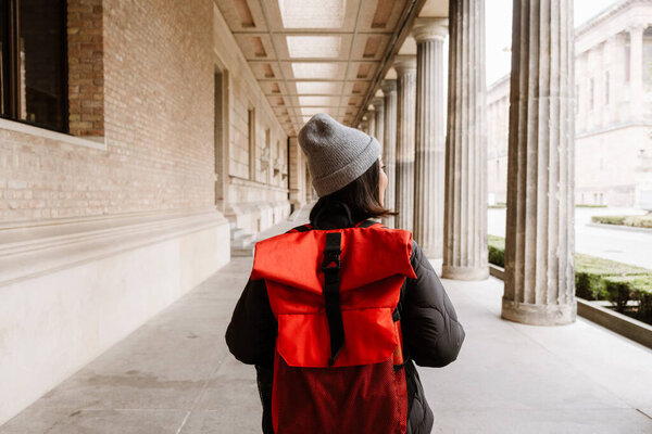 Back view of young asian woman tourist with backpack walking through the old city street