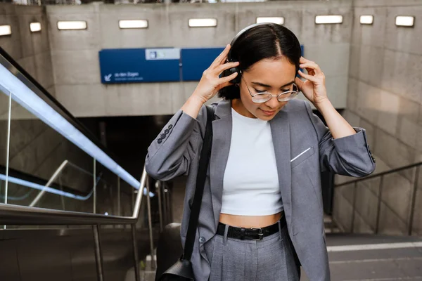 Young Asian Woman Wearing Suit Putting Headphones While Going Stairs — Stockfoto