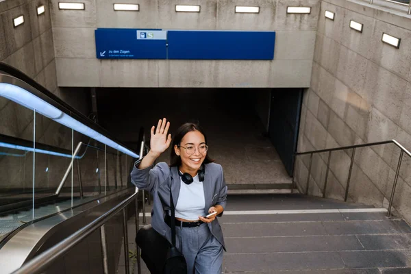 Joyful Young Asian Woman Wearing Suit Waving Hand While Going — Stok fotoğraf