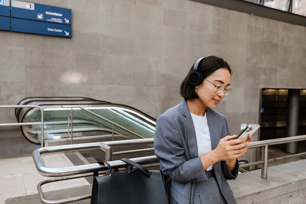 Young Asian Woman Headphones Using Smartphone While Standing Outdoors Escalator — Stok fotoğraf