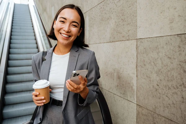 Jovem Sorrindo Asiático Mulher Segurando Café Telefone Celular Enquanto Escada — Fotografia de Stock