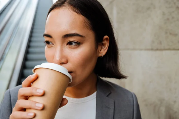 Young Asian Woman Wearing Suit Drinking Coffee While Standing Escalator — Zdjęcie stockowe