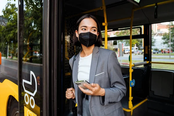 Tıbbi Maskeli Genç Asyalı Kadın Elinde Akıllı Bir Telefonla Otobüste — Stok fotoğraf