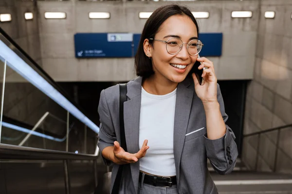 Joven Sonriente Mujer Asiática Gafas Hablando Teléfono Móvil Mientras Está —  Fotos de Stock