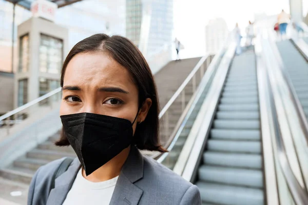 Young Asian Displeased Woman Medical Mask Standing Escalator Outdoors — Stockfoto