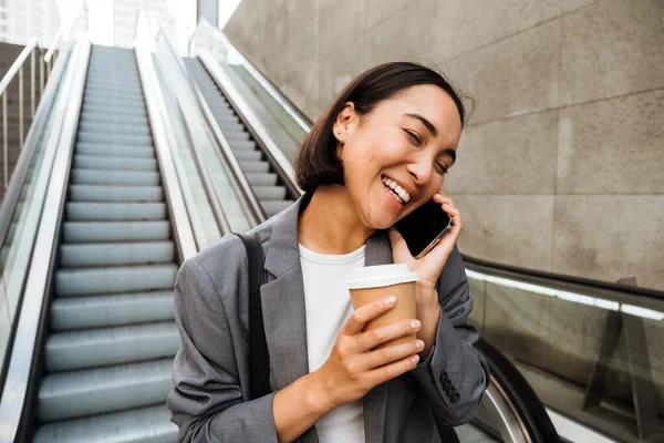 Young Asian Woman Talking Cellphone Drinking Coffee While Standing Escalator — Stockfoto