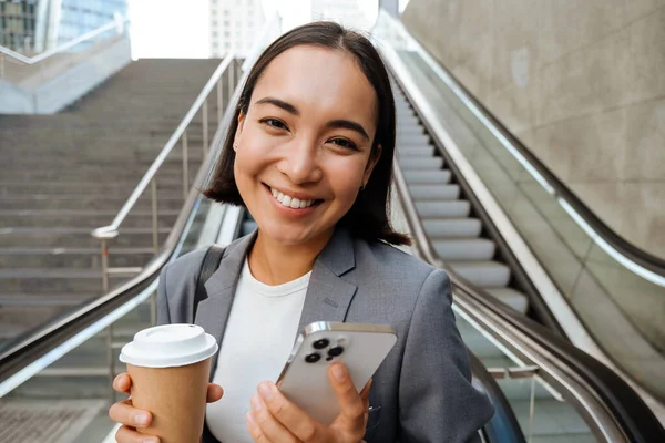 Young Asian Woman Smiling Camera Holding Mobile Phone Coffee While — Zdjęcie stockowe