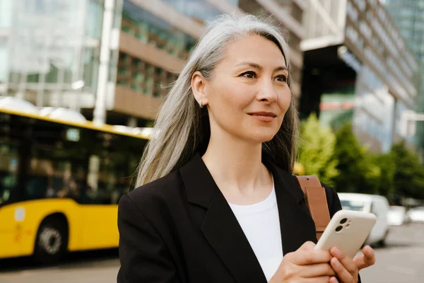 Серо Азиатская Женщина Улыбается Пользуется Мобильным Телефоном Городской Улице — стоковое фото