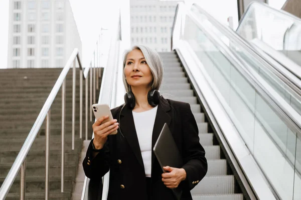 Olgun Asyalı Kadın Asansörde Dururken Cep Telefonu Kullanıyor — Stok fotoğraf
